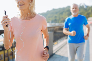 Close up of elderly woman listening to music and running