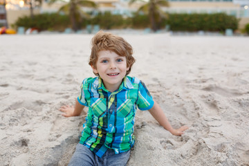 little kid boy running on the beach of ocean