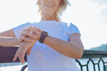 Smiling elderly woman looking at her smart watch