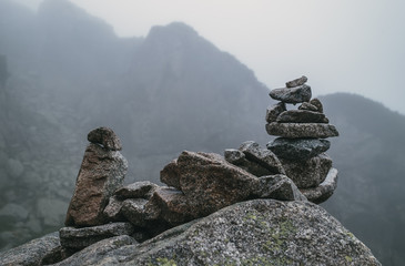 Human-made pile of stones - cairn as way marker in foggy mountain © Soloviova Liudmyla