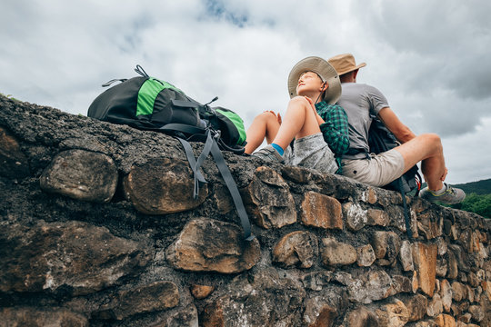 Father and son backpacker traveler rest together on old stone wall