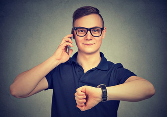 Man with wrist watch, talking on a phone being on time for meeting.