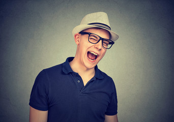 Cheerful young man in a white hat winking over gray wall background