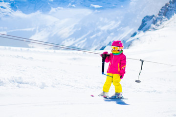Fototapeta na wymiar Child on ski lift in snow sport school in winter mountains