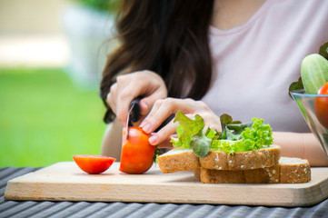 Obraz na płótnie Canvas Asian woman cut tomato for making sandwich