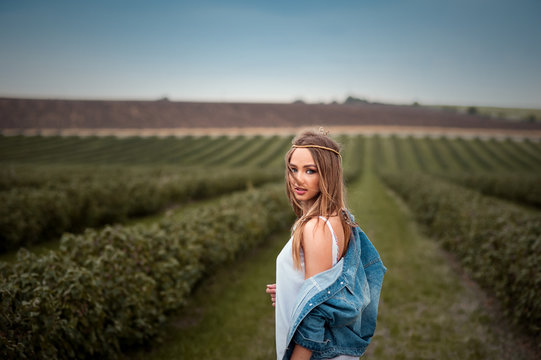 boho hippie girl with jeans jacket and white dress in field
