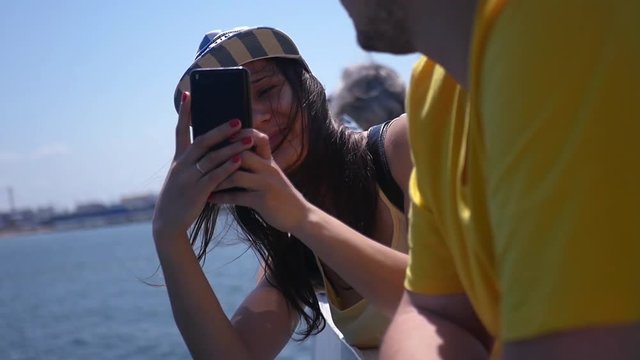 Girl takes pictures on the phone while standing near the water. HD, 1920x1080. slow motion.
