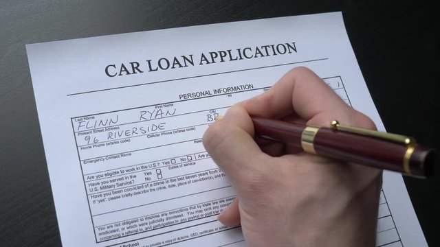 Car loan application form is filled by a hand. This form is randomly filled with no real names or numbers.