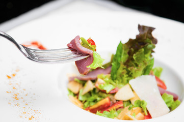 Smoked duck breast salad with parmesan cheese on fork