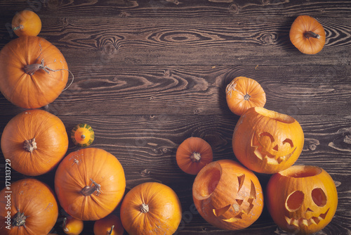 Halloween pumpkins over wooden background, top view, flat lay with copy space for text, toned image