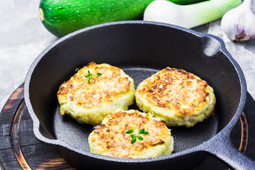 Roasted zucchini fritters in cast iron skillet. Selective focus, space for text.