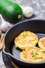 Zucchini fritters in cast iron skillet and ingredients.  Selective focus, close up.