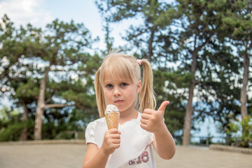 Fototapeta premium Little adorable blonde girl eating ice-cream outdoors.