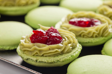Green macaroons with pistachios ganache cream and raspberries confit filling