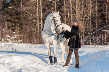 Nice girl and white horse in a forest in a winter