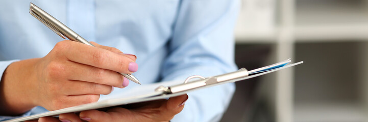Female arm in suit hold silver pen and pad