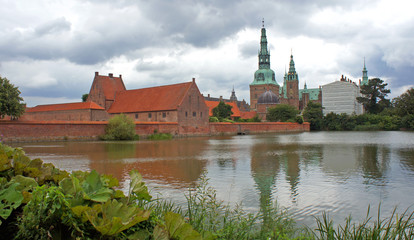 View of Frederiksborg castle (slot), Renaissance architecture, reflection of the palace in water, cloudy weather, Hillerod, Denmark