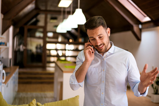 Man Talking On The Phone In Kitchen At Home