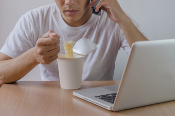 Freelance man work hard, eat instant noodle, contact customer and work business to success.