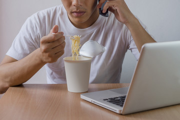 Freelance man work hard, eat instant noodle, contact customer and work business to success.