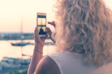 A woman photgraphyng a sail boat in the pier of Ortigia ( Siracusa -Sicily - Italy)