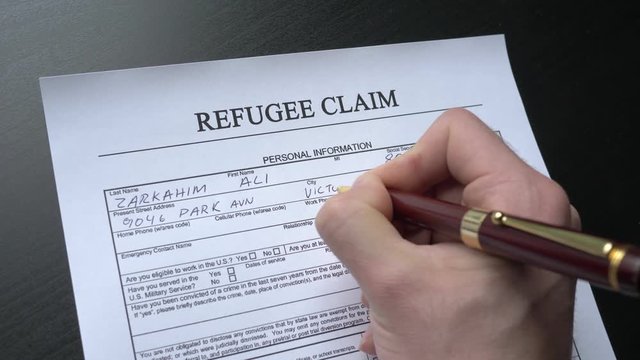 Filing a refugee claim document by hand. This form is randomly filled with no real names or numbers.