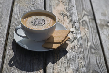 Cup of coffee with biscuits on rustic wooden table