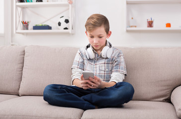 Obraz premium Teenager messaging online on smartphone in living room at home