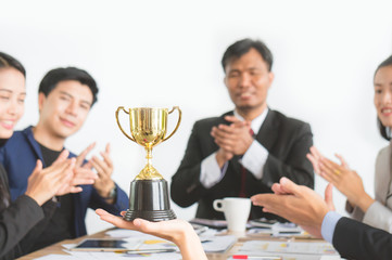 Businessman with colleagues achieve target and successful showing award trophy