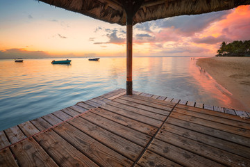 Perspective view of a wooden pier that create two amazing frame at sunset,tropical beach in Mauritus island
