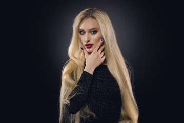 Beautiful model with long blonde salon hair and red lips and make up in the studio