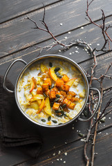 Gluten free pumpkin and apple porridge. Nut milk oatmeal with pumpkin, apples and honey on wooden brown background. Delicious healthy vegetarian breakfast