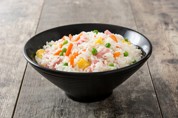 Chinese fried rice with vegetables and omelette on wooden table

