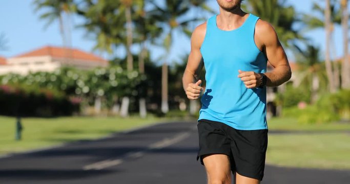 Runner looking at his heart rate monitor, activity tracker smartwatch. Active athlete man looking at his smart watch using app on watch while running outside on road. Male athlete.