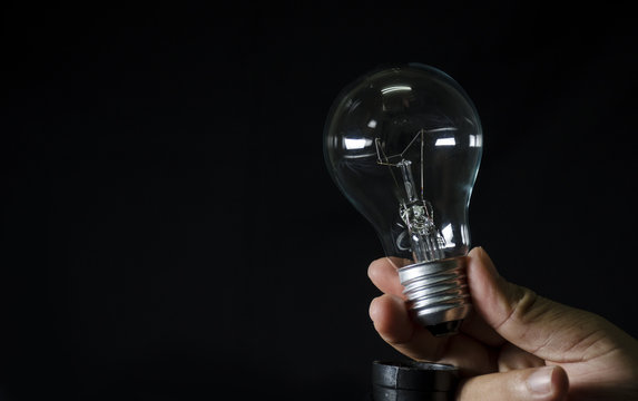 bulb light in human hand and black background
