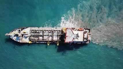 Suction Dredger ship working near the port - with mud, Pollution, brown Muddy water - aerial tip...