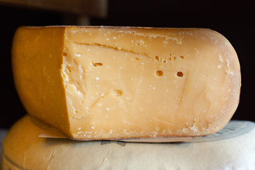 Hard cheese as wheel and piece on grocery shop shelf closeup