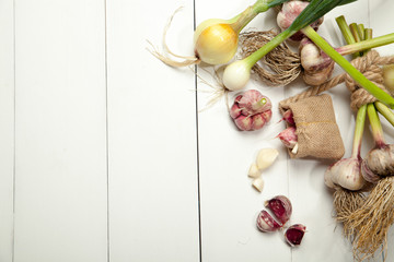 Fresh garlic and onions on a white wooden table.