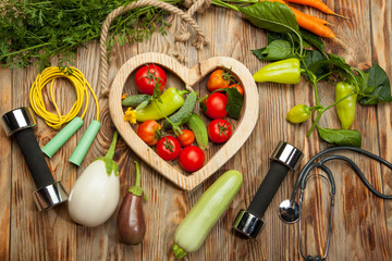 Fresh vegetables, sports, diet on a wooden background