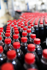 Obraz premium Bottling factory - Black juice or soft drink bottling line for processing and bottling juice into bottles. Selective focus. 