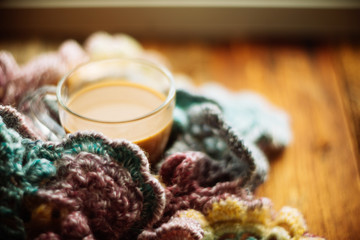 cozy soft gray blanket with a big red cup on the background of a window decorated with frost / warming moments winter holidays