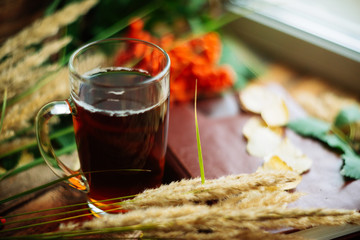 green circle in the scarf, the window with maple leaves and drops after rain in autumn / season when you need warm drinks