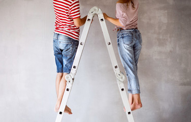 Unrecognizable couple painting walls in their house.