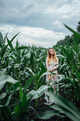 Beautiful girl stands in the field of young corn. Agriculture.