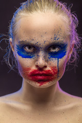 female portrait with creative multicolored makeup on black background