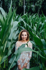 Beautiful girl stands in the field of young corn. Agriculture.