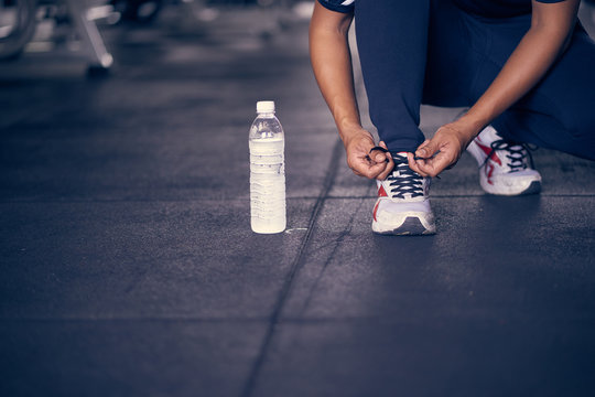 Man tying shoelaces at sneaker in the gym.