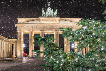 Das Brandeburger Tor in Berlin bei Nacht mit weihnachtlichem Tannenzweig und Schneefall © moofushi
