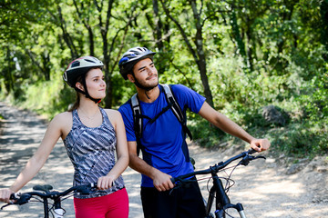 happy young couple riding bicycle in countryside during summer