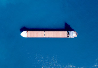 Large bulk carrier ship sailing in open ocean - top down aerial view